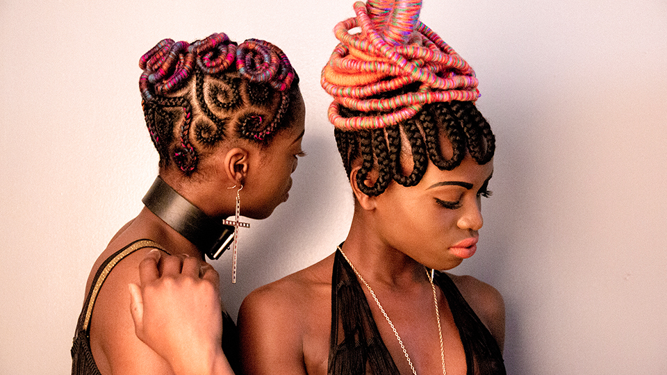 black and white photo of two black models in colorful intricate braids and vintage fashion