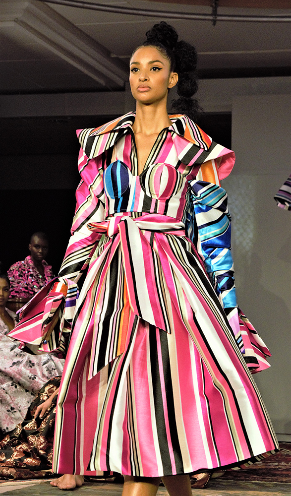 Model wearing a broad-shouldered, multicoloured striped Selam Fessahaye dress on the AW19 runway